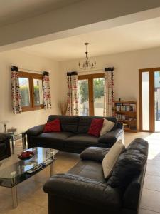 a living room with a black couch and a glass table at EPISKOPI VILLA, Luxury 4 Bedroom with Pool - Limassol in Limassol