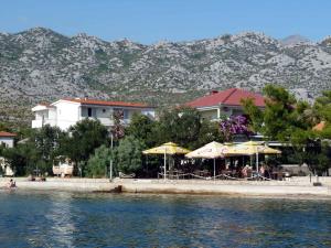 a restaurant with tables and umbrellas next to the water at Apartments Seline/Paklenica Riviera 36550 in Seline