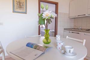 a white table with a vase of flowers and two cups at Apartments in Capoliveri/Insel Elba 23660 in Capoliveri