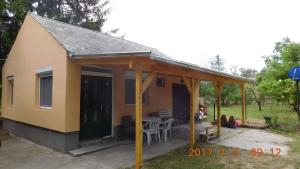 Casa pequeña con porche y mesa en Holiday home in Balatonmariafürdo 26831 en Balatonmáriafürdő