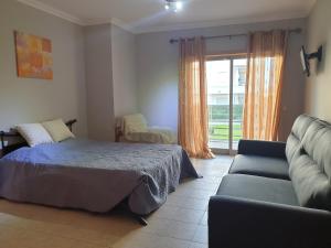 a bedroom with a bed and a couch and a window at Lovely Studio Marta on the beach Falesia, Albufeira in Albufeira