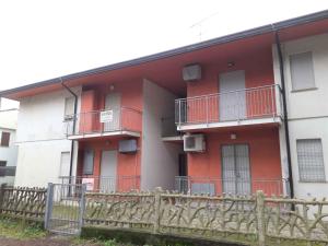 um edifício vermelho e branco com varandas e uma cerca em Apartments in Rosolina Mare 25011 em Rosolina Mare