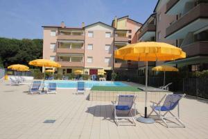 a group of chairs and umbrellas next to a pool at Apartments in Rosolina Mare 33097 in Rosolina Mare