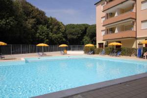 a swimming pool with chairs and umbrellas next to a building at Apartments in Rosolina Mare 33097 in Rosolina Mare