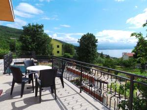 balkon ze stołami i krzesłami oraz widokiem na wodę w obiekcie Apartments in Icici 15136 w mieście Ičići