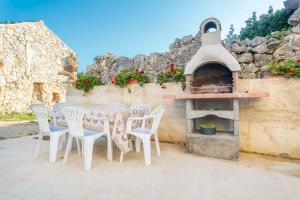 einen Tisch und Stühle vor einem Pizzaofen in der Unterkunft Apartments in Cizici - Insel Krk 31083 in Čižići