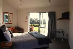 1 dormitorio con 1 cama y puerta corredera de cristal en Omau Settlers Lodge Motel en Westport