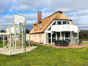 a large house with a thatched roof and a basketball hoop at 8 person holiday home in Bl vand in Blåvand