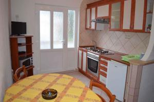 een kleine keuken met een tafel met een geel tafelkleed bij Apartment in Selce 5869 in Selce