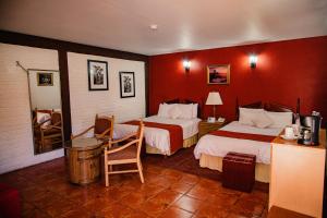 a hotel room with two beds with red walls at HOTEL BOUTIQUE EL VIEJO MUNDO in Hidalgo del Parral