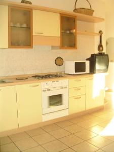 een keuken met een wit fornuis en een magnetron bij Apartment in Rosolina Mare 24985 in Rosolina Mare