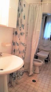 een badkamer met een wastafel, een toilet en een douchegordijn bij Apartment in Rosolina Mare 24985 in Rosolina Mare