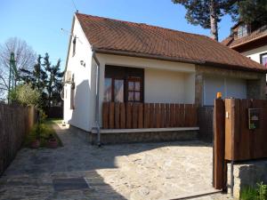 een klein wit huis met een houten hek bij Holiday Homes in Balatonmariafürdo 19438 in Balatonkeresztúr