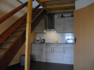 uma cozinha com armários brancos e uma escada de madeira em Apartments in Lübben Spreewald 26522 em Steinkirchen