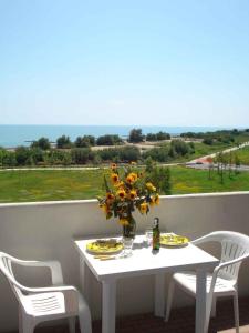 a white table with a vase of flowers on a balcony at Apartments Porto Santa Margherita 25671 in Porto Santa Margherita di Caorle