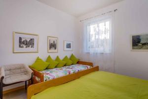 - une chambre avec un lit doté d'oreillers verts et d'une chaise dans l'établissement Apartment in Mali Losinj 15009, à Čunski