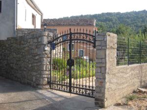 a stone fence with an iron gate in front of a building at Apartment in Veli Losinj 26456 in Veli Lošinj