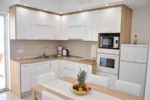 een keuken met witte kasten en een tafel met een fruitschaal bij Apartment in Ljubac/Zadar Riviera 31380 in Ljubač
