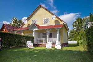 una casa con cuatro sillas blancas en el patio en Holiday home in Balatonmariafürdo 35399 en Balatonmáriafürdő