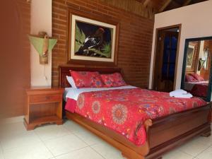 um quarto com uma cama com um edredão vermelho em Hostal Casa Cultural Mindo em Mindo