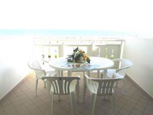 uma mesa branca e cadeiras com um arranjo de flores sobre ela em Apartment in Bibione 24595 em Bibione