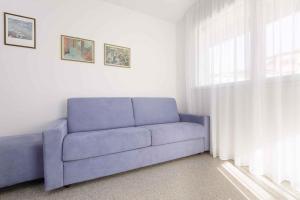 - un canapé bleu dans le salon doté d'une fenêtre dans l'établissement Apartment in Lignano Sabbiadoro 21778, à Lignano Sabbiadoro