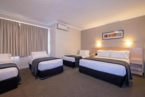 a hotel room with two beds and a television at Maclin Lodge Motel in Campbelltown