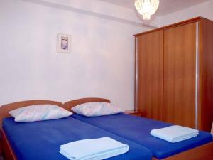 ein blaues Bett mit zwei Kissen und einem Holzschrank in der Unterkunft Apartment in Omisalj/Insel Krk 34661 in Omišalj