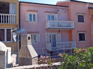 ein rosafarbenes Haus mit einer Treppe und einem Balkon in der Unterkunft Apartment in Omisalj/Insel Krk 34661 in Omišalj