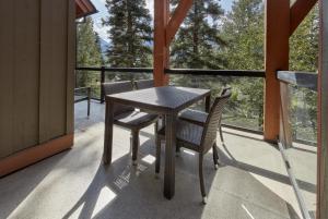 una mesa y sillas en un porche con vistas a los árboles en Star Suite -Luxurious condo with 3 fireplaces, and open Pool!, en Canmore