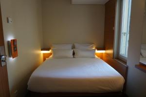 a bedroom with a bed with white sheets and a window at easyHotel Berlin Hackescher Markt in Berlin