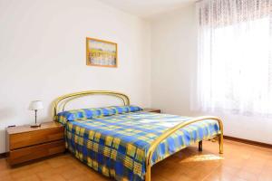 リニャーノ・サッビアドーロにあるApartments in Lignano 21670のベッドルーム1室(青と黄色の毛布付きのベッド1台付)