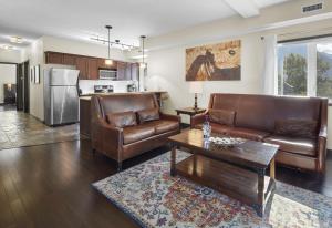 a living room with two leather couches and a table at Sundance Suite - Beautiful Condo With Open Pool And Hot Tub in Canmore