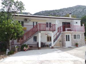 Una casa blanca con una escalera roja. en Apartment Karlobag/Velebit Riviera 27804 en Karlobag