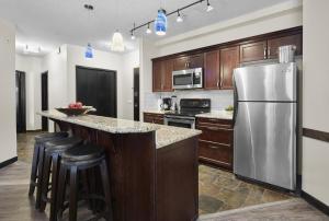 a kitchen with wooden cabinets and a stainless steel refrigerator at Mountain Fun - With Open Pool And Hot Tub in Canmore