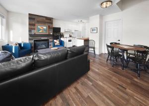 a living room with a black leather couch and a table at Mountain Gate - Pet Friendly 2BR w Mountain Views and open hot tub in Canmore