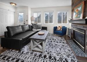 a living room with a black leather couch and a fireplace at Mountain Gate - Pet Friendly 2BR w Mountain Views and open hot tub in Canmore