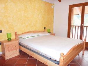 a bedroom with a bed with a wooden frame and a window at Apartments in Comano 24163 in Comano Terme