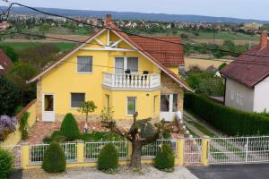 una casa gialla con una recinzione bianca di Apartments in Alsopahok/Balaton 27597 ad Alsópáhok