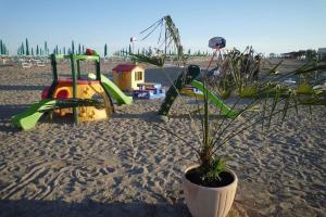 uma planta num vaso numa praia com um parque infantil em Apartments in Eraclea Mare 25693 em Eraclea Mare