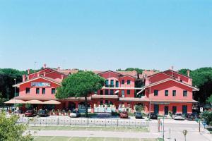 a large red building with cars parked in a parking lot at Apartment in Rosolina Mare 27385 in Rosolina Mare