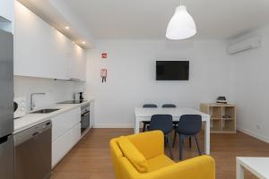 une cuisine avec une chaise jaune et une table dans l'établissement AL - Apartamentos Vista Mar, à Quarteira