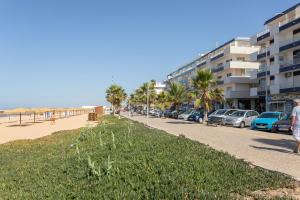 una calle junto a una playa con palmeras y edificios en AL - Apartamentos Vista Mar, en Quarteira