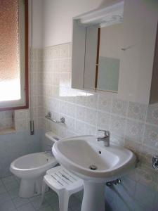 ein weißes Bad mit einem Waschbecken und einem WC in der Unterkunft Apartments in Eraclea Mare 25611 in Eraclea Mare
