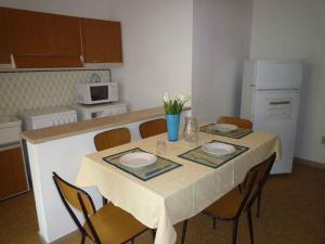エラクレア・マーレにあるApartments in Eraclea Mare 25611のキッチン(テーブル、椅子、白い冷蔵庫付)