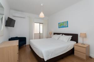 une chambre avec un lit blanc et une chaise bleue dans l'établissement AL - Apartamentos Vista Mar, à Quarteira