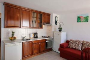 a kitchen with wooden cabinets and a red couch in a room at Apartment in Silo/Insel Krk 13587 in Šilo