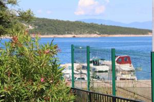 a fence next to a body of water with boats at Apartment in Silo/Insel Krk 13583 in Šilo