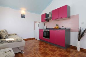 a kitchen with pink cabinets and a couch in a room at Apartment in Silo/Insel Krk 13586 in Šilo