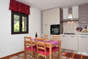 a kitchen with a table with chairs and a bottle of wine at Two-Bedroom Apartment in Siracusa II in Ognina